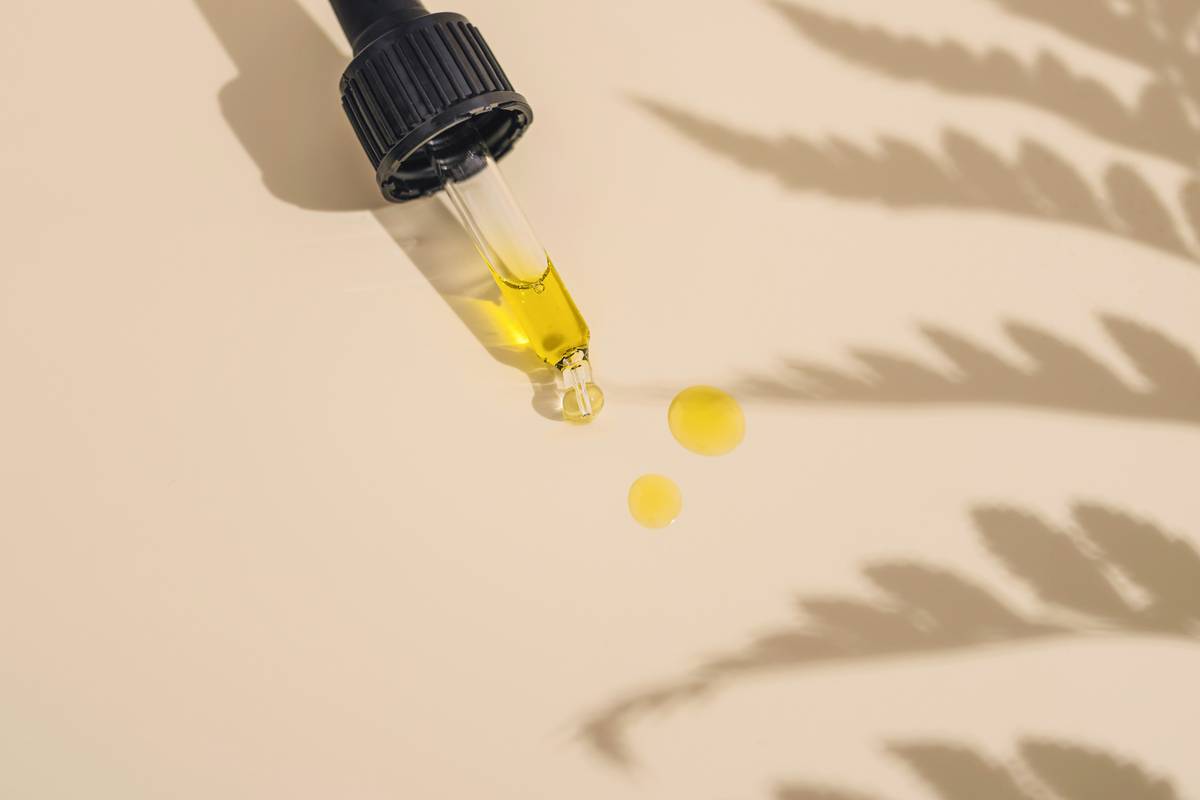 Skincare Oils: Close-up of five amber glass dropper bottles labeled jojoba, squalane, rosehip, tamanu, and marula oils on a bamboo tray